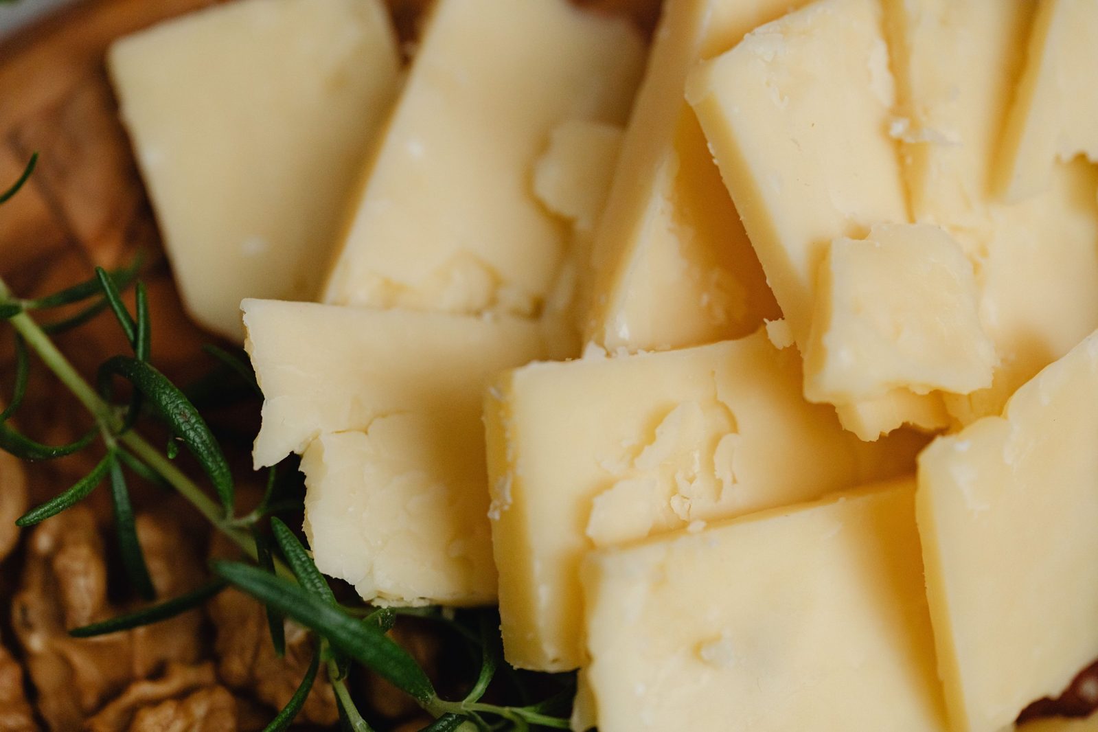 Chunks of Parmigiano Reggiano with rosemary and walnuts on a wooden board